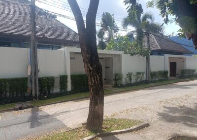 Exterior view of the property with a wall, gate, and tree