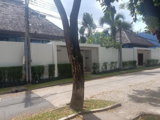 Exterior view of the property with a wall, gate, and tree