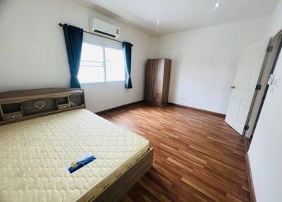 Spacious bedroom with wooden floors and a window with dark curtains