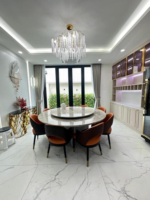 Elegant dining room with a round marble table, chandelier, and large windows