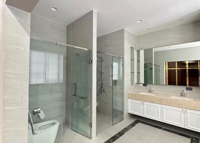 Modern bathroom with double sinks, glass shower, and toilet