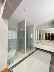 Modern bathroom with double sinks, glass shower, and toilet