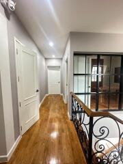 Bright hallway with wooden floor and ornamental railing