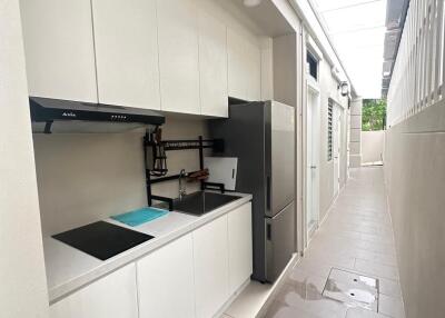 Modern narrow kitchenette with white cabinets and appliances