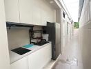 Modern narrow kitchenette with white cabinets and appliances