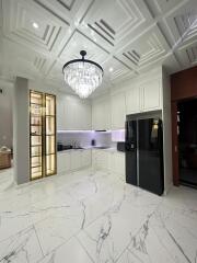 Modern kitchen with white cabinets, marble flooring, and a large chandelier