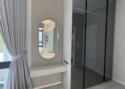 Modern bedroom with floor-to-ceiling windows, mirrored built-in wardrobe, and makeup area with round mirror