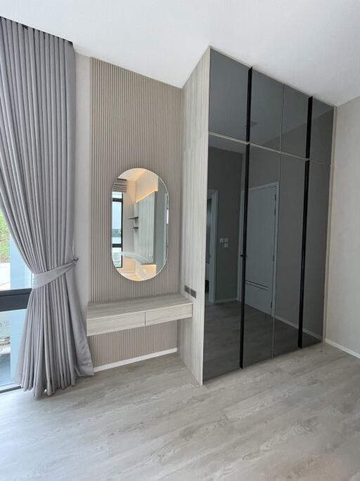 Modern bedroom with floor-to-ceiling windows, mirrored built-in wardrobe, and makeup area with round mirror