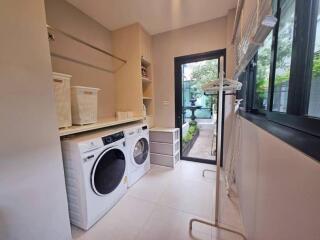 Modern laundry room with washer and dryer, ample storage, and large windows