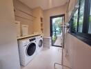 Modern laundry room with washer and dryer, ample storage, and large windows