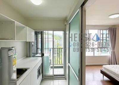 Modern kitchen area with adjacent bedroom and large windows.