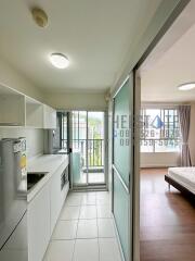 Modern kitchen area with adjacent bedroom and large windows.