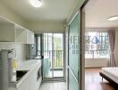 Modern kitchen area with adjacent bedroom and large windows.