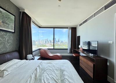 Modern bedroom with city view, stylish furniture, and a large window