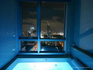 Bathroom with a large window and night city view