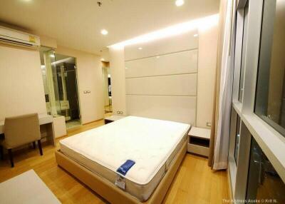 modern bedroom with large bed, desk, and glass-enclosed bathroom