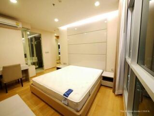 modern bedroom with large bed, desk, and glass-enclosed bathroom