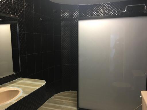 Modern bathroom with black tiled walls and frosted glass shower