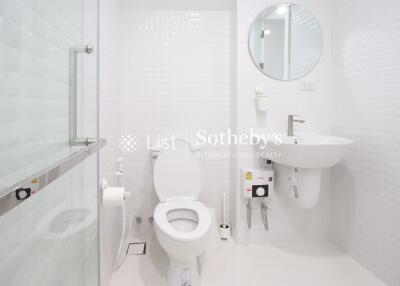 Modern white bathroom with glass shower door and round mirror