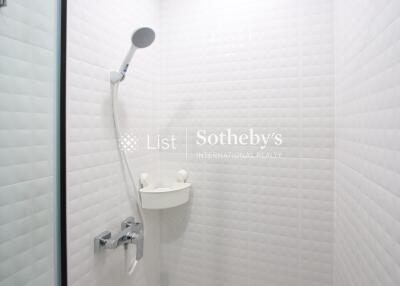 Modern bathroom shower area with white tiled walls and a mounted showerhead.