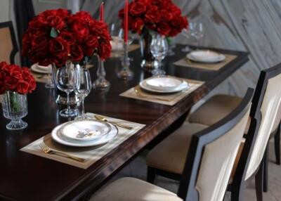 Elegant dining room with formal place settings and red flower arrangements