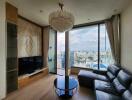 Modern living room with a chandelier, large windows, and city view