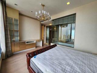 Spacious modern bedroom with a large window, chandelier, and built-in cabinets