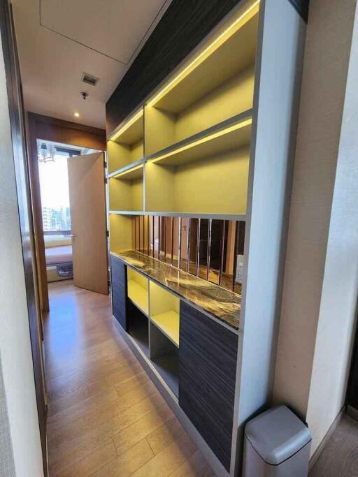 Narrow hallway with built-in shelving, wooden flooring and ambient lighting