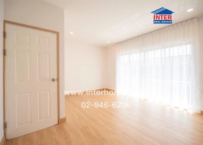 Spacious living area with wooden flooring and large windows