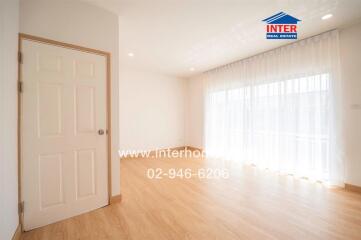 Spacious living area with wooden flooring and large windows