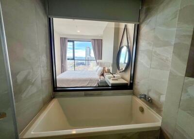 Bathroom view with bathtub and a window showing the bedroom