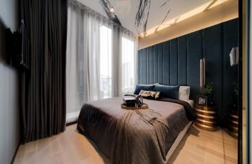 Modernly designed bedroom with large windows, dark accent wall, and elegant decor