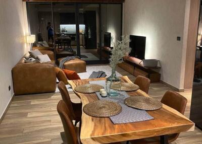 Modern living and dining area with wooden table, leather chairs, sofa, and TV