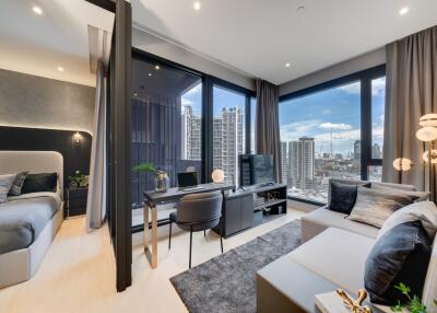 Modern living room with adjoining bedroom, desk setup, and city view