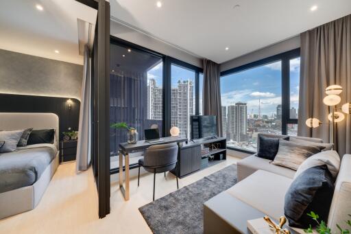 Modern living room with adjoining bedroom, desk setup, and city view