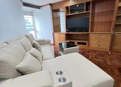 Spacious living room with a white sectional sofa and wooden built-in entertainment center