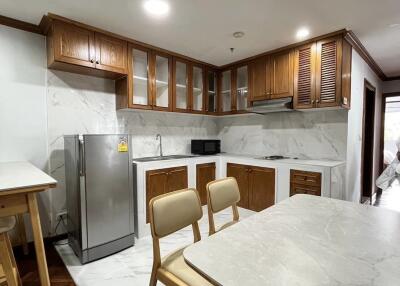 Modern kitchen with wooden cabinets, marble countertops, and dining area