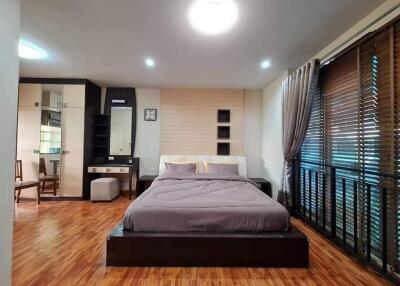 Spacious modern bedroom with wooden flooring, large windows, and ample storage