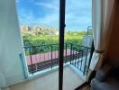 Living area with glass door leading to balcony overlooking a green field