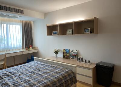 Cozy bedroom with a window, desk, shelves, and a bed