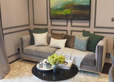 Comfortable living room with a grey sofa and decorative pillows, modern artwork, and a round coffee table