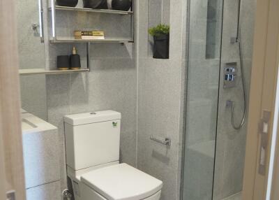 Modern bathroom with toilet, glass shower enclosure, and decorative shelves