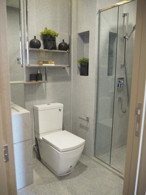 Modern bathroom with toilet, glass shower enclosure, and decorative shelves