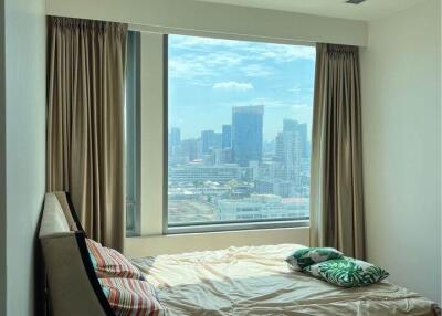 A bedroom with a large window and a view of the city skyline