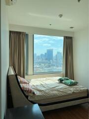 A bedroom with a large window and a view of the city skyline