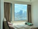 A bedroom with a large window and a view of the city skyline