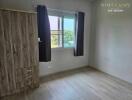 Bedroom with wooden wardrobe, window, and gray curtains