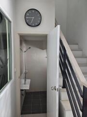 Small bathroom with a sink, shower, and wall clock