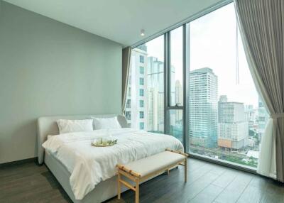 A modern bedroom with large glass windows and city view