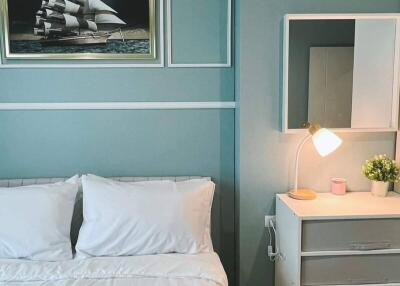 Well-lit bedroom with a framed ship painting, a white bed, and a nightstand